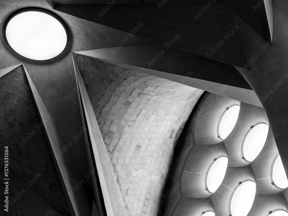 Fototapeta premium Interior featuring a combination of shapes and materials. The brickwork is arranged in a herringbone pattern, with additional circular light fixtures in the curved sections. Black and white image.