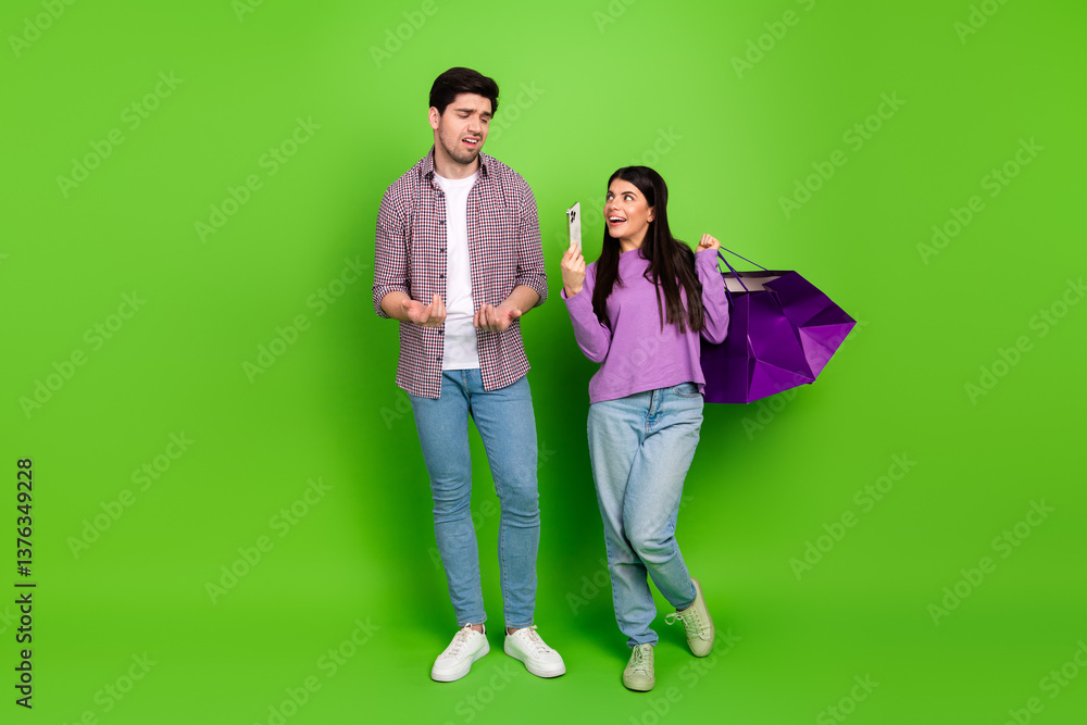 Obraz premium Young couple enjoying a shopping experience while bonding together on a vibrant green background showcasing joyful emotions