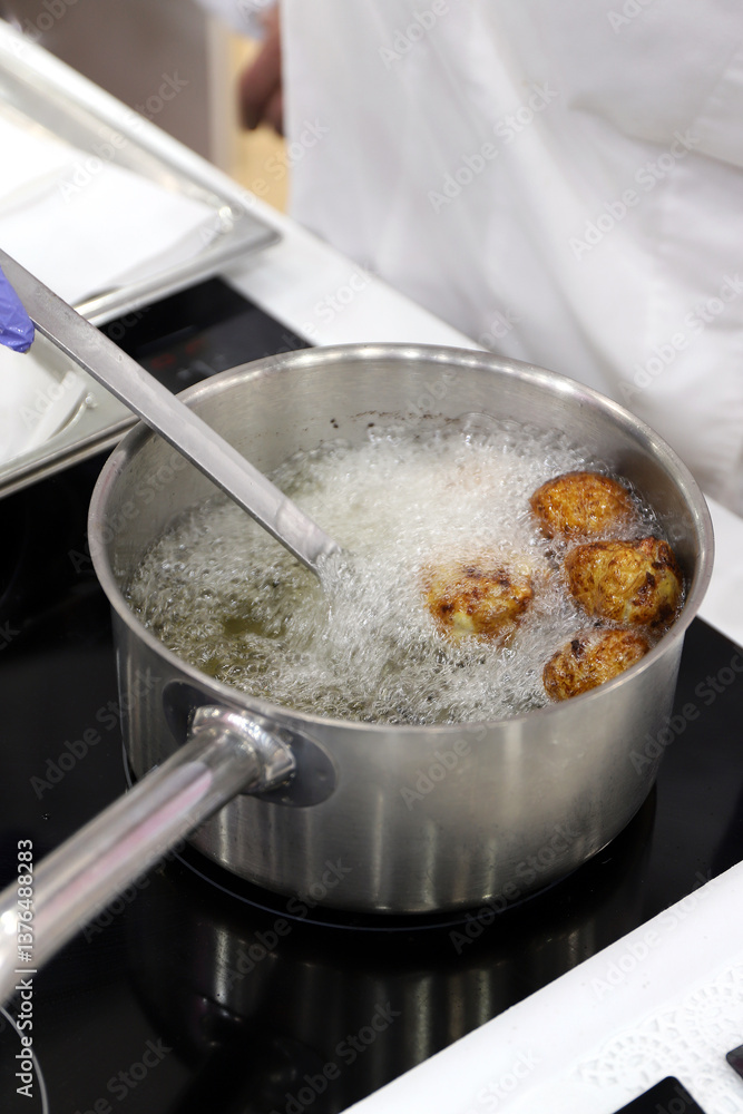 chef cocinado buñuelos de carne en una hoya de aceite hirviendo en la cocina chef cocinado buñuelos de carne en una hoya de aceite hirviendo en la cocina