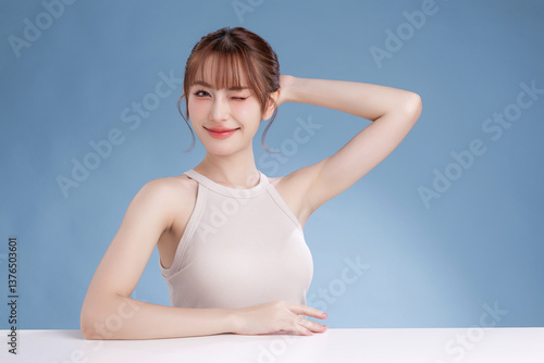 Beautiful young Asian woman model with bangs and natural makeup on face clean fresh skin on isolated blue background. Cute girl portrait, Facial treatment, Body care, Beauty and Spa.