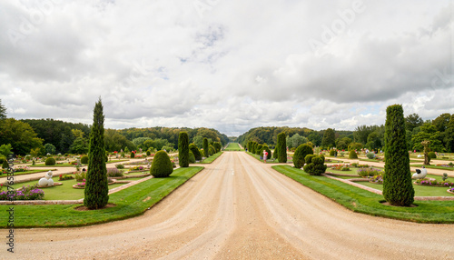 Cemetery pathway with manicured gardens under cloudy sky