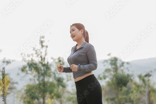 A young woman pauses during her run to tighten her shoelaces. A gentle breeze and birdsong refresh her before she stretches and continues running.