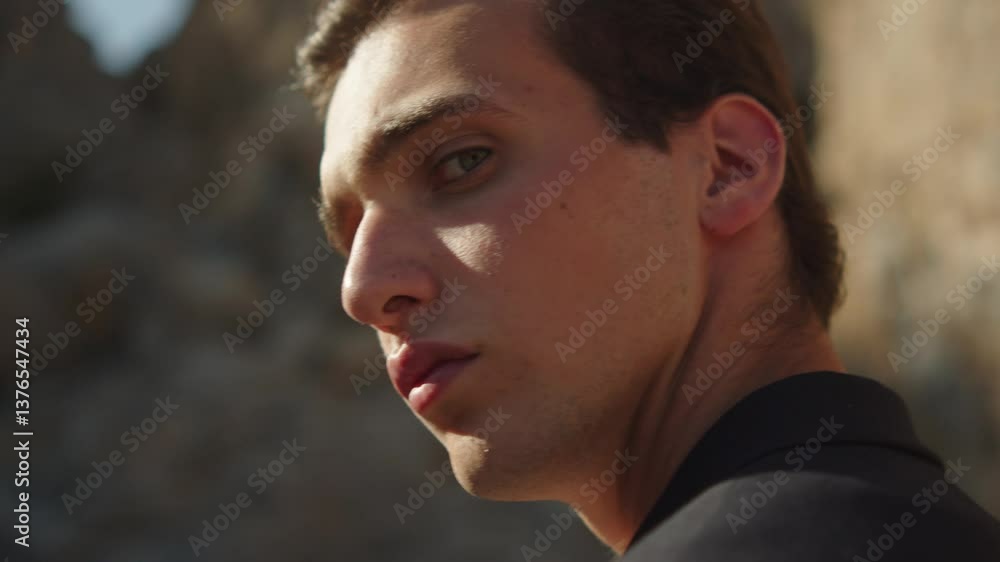 Handsome young guy model walking and turns around for camera. Male fashion model in a blue business suit looking back, on nature. Young confident man looks back and looking to the camera. Handsome young guy model walking and turns around for camera. Male fashion model in a blue business suit looking back, on nature. Young confident man looks back and looking to the camera.