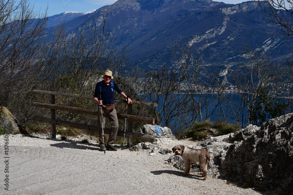 Mann und sein Lagotto Romagnolo Hund wandern oberhalb vom Gardasee
