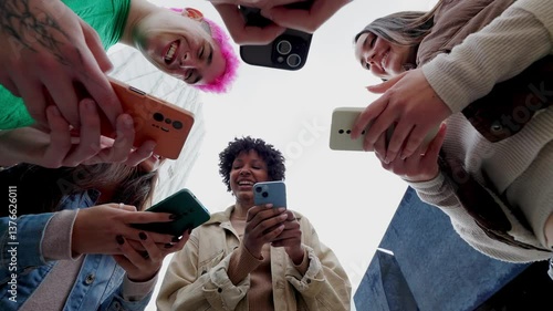 Wallpaper Mural Low angle view of young group of people using mobile phones together at city street. Diverse college student friends watching social media content on cell. Cellphone addicted people concept. Torontodigital.ca