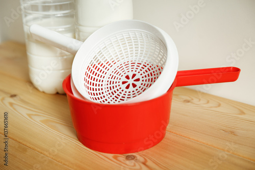 Plastic equipment for making soft cheese and cottage cheese at home. A white uniform, a red ladle.