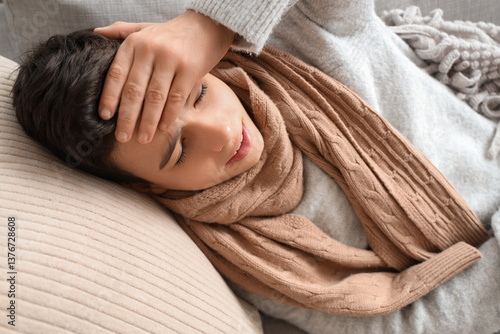 Sick little boy lying on so...