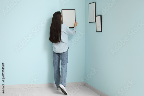 Young woman hanging picture...