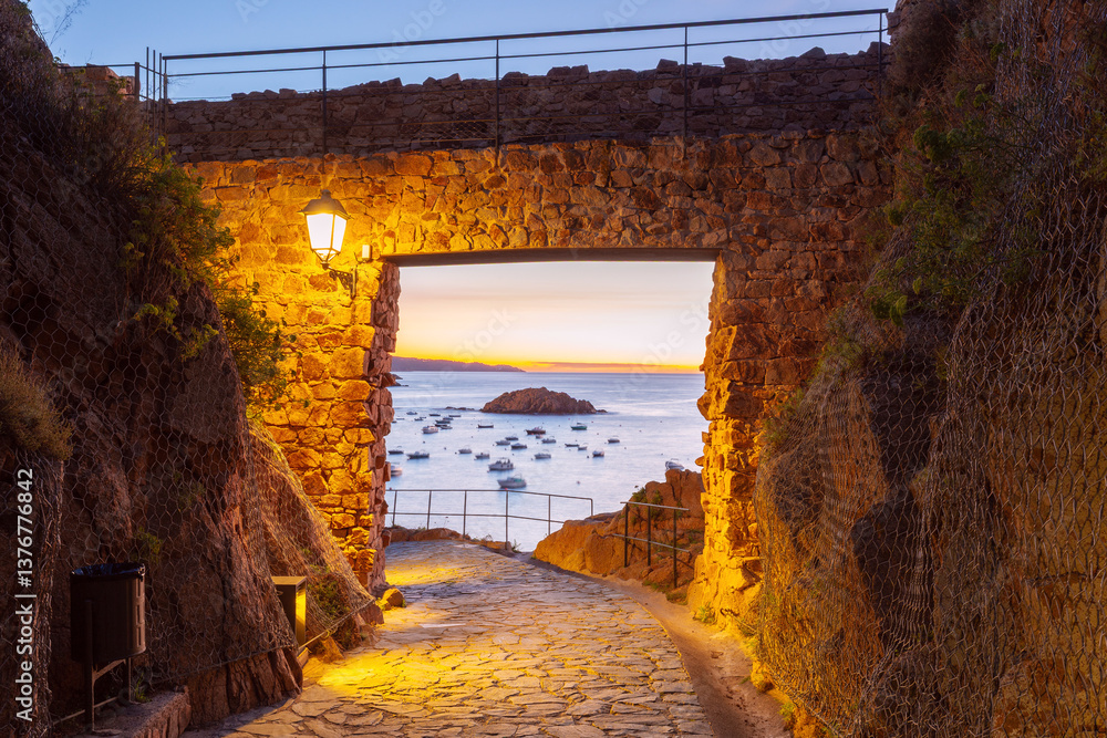 Stone gate entrance to Vila Vella fortress at sunset in Tossa de Mar, Spain