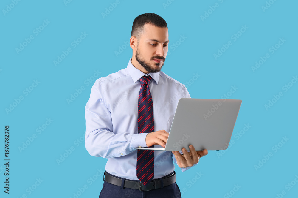 Young businessman with tie using laptop on blue background Young businessman with tie using laptop on blue background