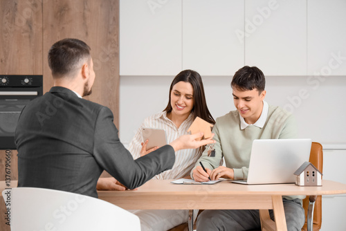 Young couple signing house ...