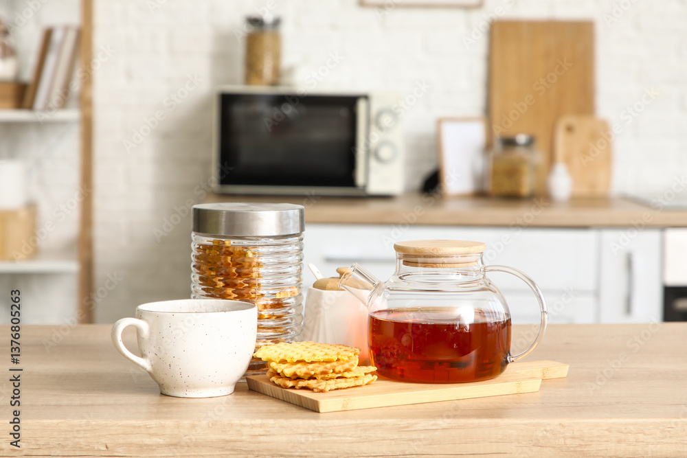 Teapot with jar of waffles and cup on table in kitchen Teapot with jar of waffles and cup on table in kitchen