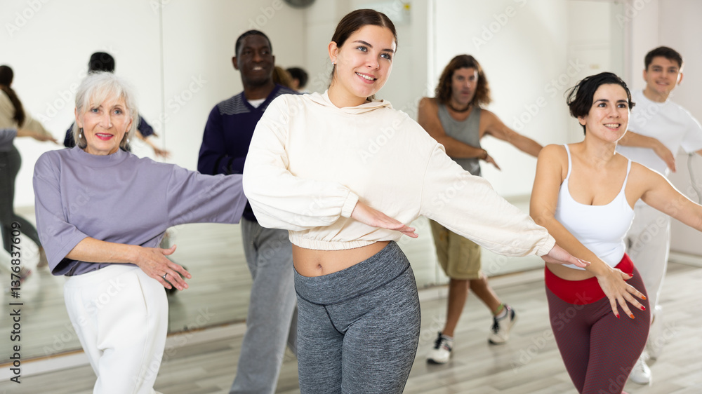 Naklejka premium Smiling attractive young girl visiting group choreography class, learning modern dynamic dances. Concept of active lifestyle