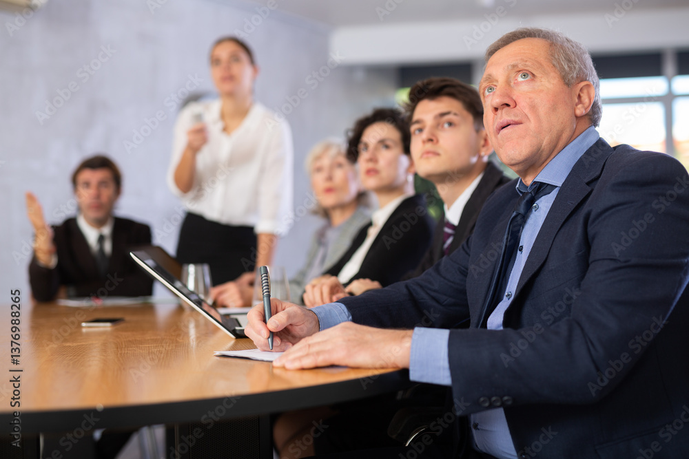 Group of businessmen attentively watching a presentation in a meeting room Group of businessmen attentively watching a presentation in a meeting room