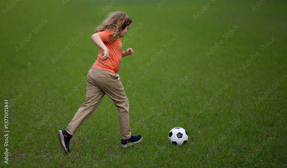 Obraz premium Kid playing football in the park. Child kicking a football ball on field. Happy boy running with a football ball. Children playing soccer outdoors. Kid play football on the grass. Summer soccer game.