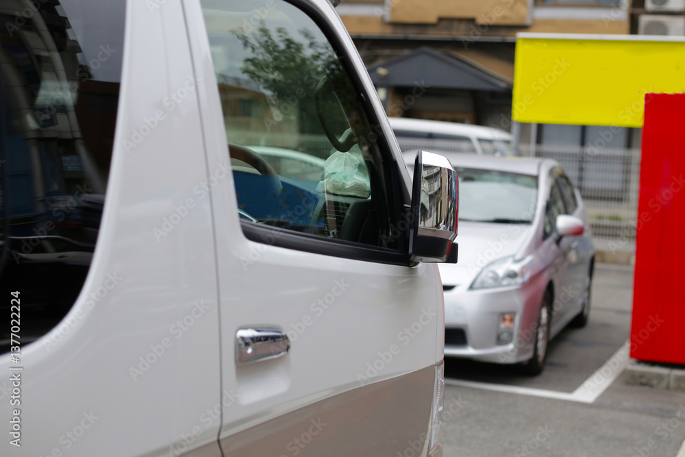 Fototapeta premium A white van's side mirror with a car in the background.