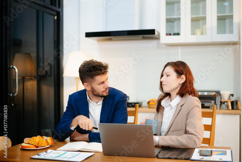 Two professionals collaborating on a business project over coffee in a cozy kitchen.