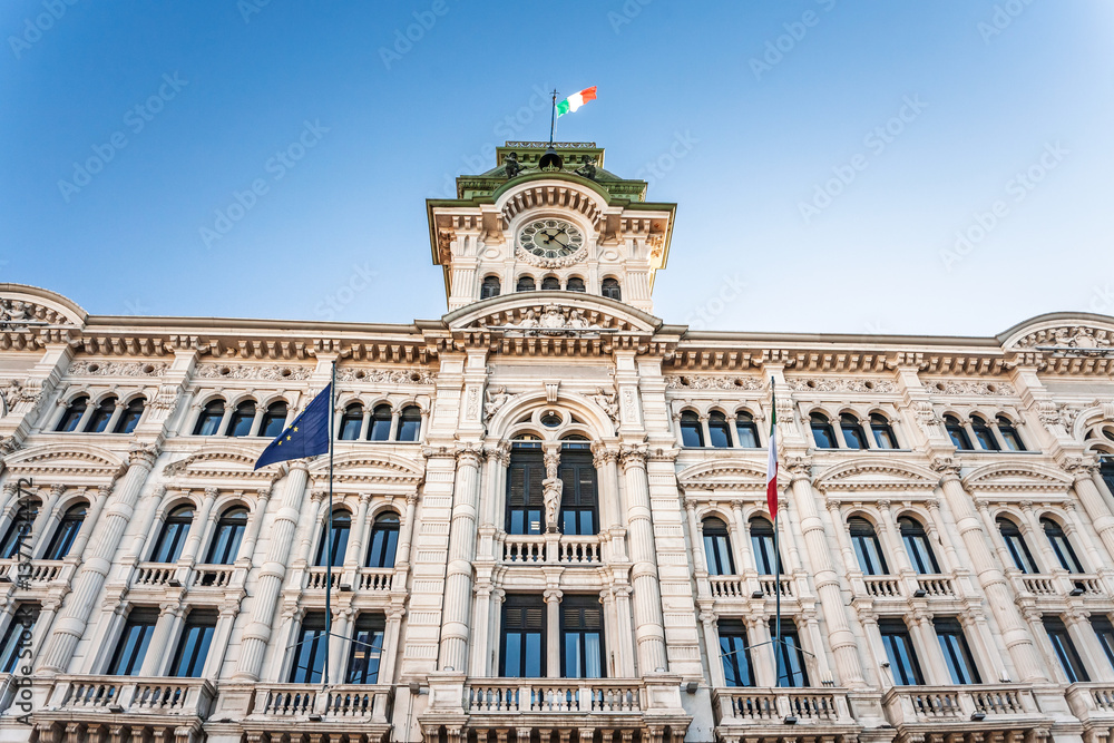 Obraz premium Facade of Trieste Palazzo del Municipio, the city hall with neoclassical architecture, clock tower, on in Piazza Unita d'Italia, Italy. It's a landmark and the seat of trieste municipal administration