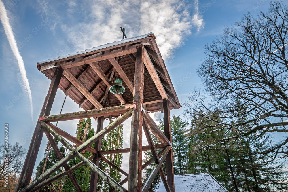 A Serbian Orthodox church bell inside a traditional wooden bell tower, set against a serene sky and snowy landscape in rural Serbia. A Serbian Orthodox church bell inside a traditional wooden bell tower, set against a serene sky and snowy landscape in rural Serbia.