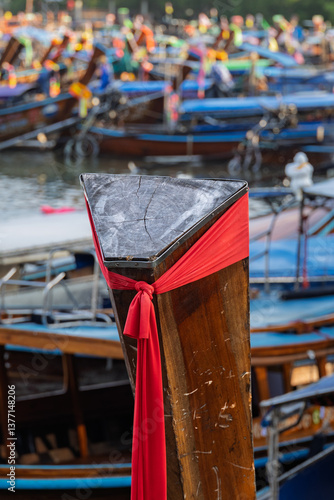 Wallpaper Mural Stand out. Close up shot of a weathered wooden long tail boat prow with a bright red cloth hanging from it near Ao Nang, Krabi. Blurred colourful boats crowded together in the background. Torontodigital.ca