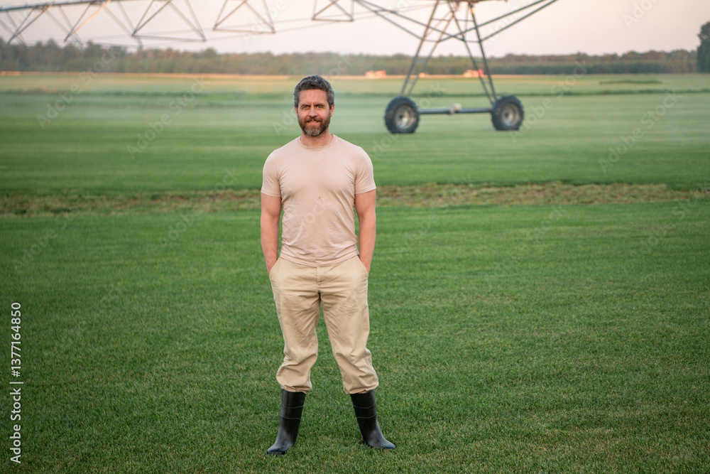 Fototapeta premium Farmer standing in a grassy field. A man harvesting vegetables on a farm. A farmer using irrigation on a farm. A man working in a green field. American farmer inspecting a harvest-ready field.