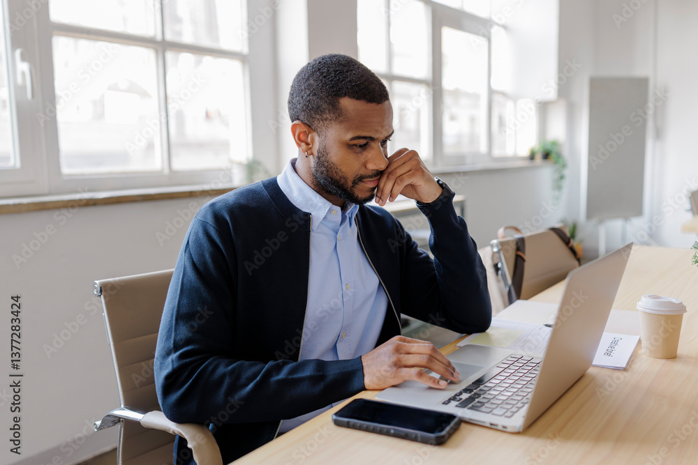 Focused formal businessman working on laptop in modern office Focused formal businessman working on laptop in modern office