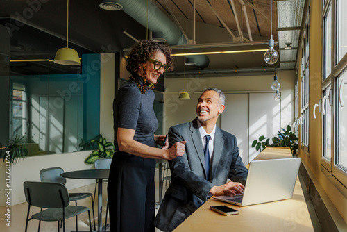 Formal business colleagues collaborating on laptop in modern office