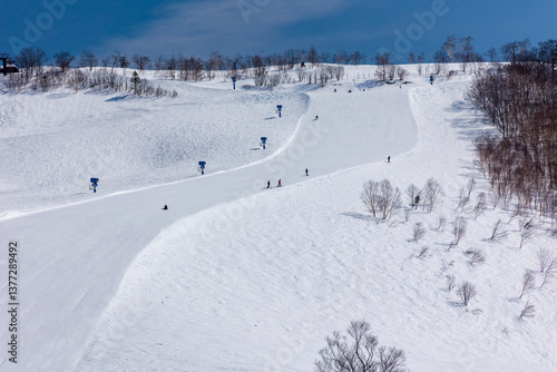 Obraz na płótnie Snowboarders descending a wide, steep ski slope on bright sunny day w salonie