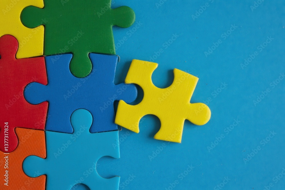 Obraz premium Colorful puzzle pieces against a bright blue background, highlighting a missing yellow piece ready to be placed.