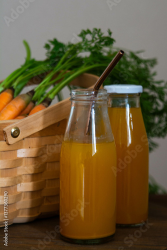 Healthy eating. Two bottles of fresh carrot juice on the table against the background of a wicker basket with carrots.