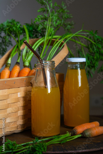 Healthy eating. Two bottles of fresh carrot juice on the table against the background of a wicker basket with carrots.