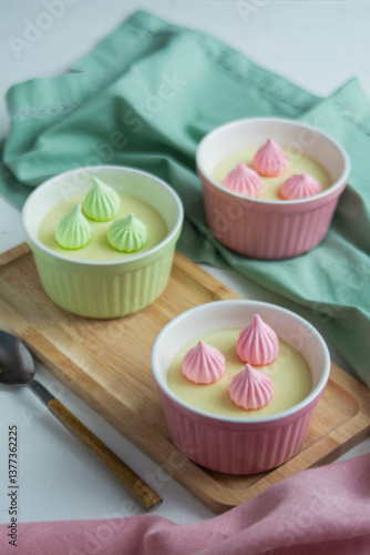 Cream dessert in colored cups on a wooden stand with colored napkins.