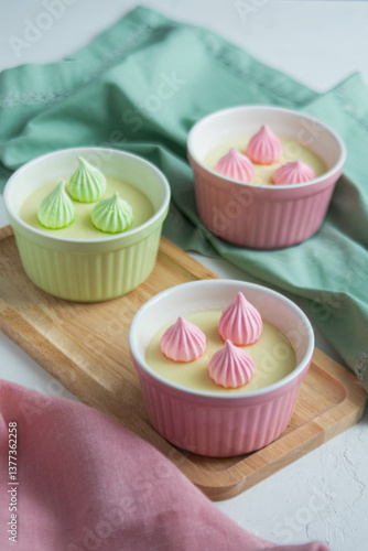 Cream dessert in colored cups on a wooden stand with colored napkins.