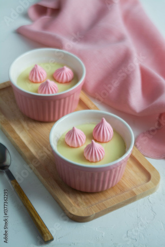 Cream dessert in colored cups on a wooden stand with colored napkins.