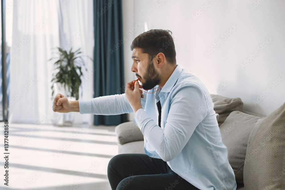 Brunette guy sitting on a coach and watching football at home
