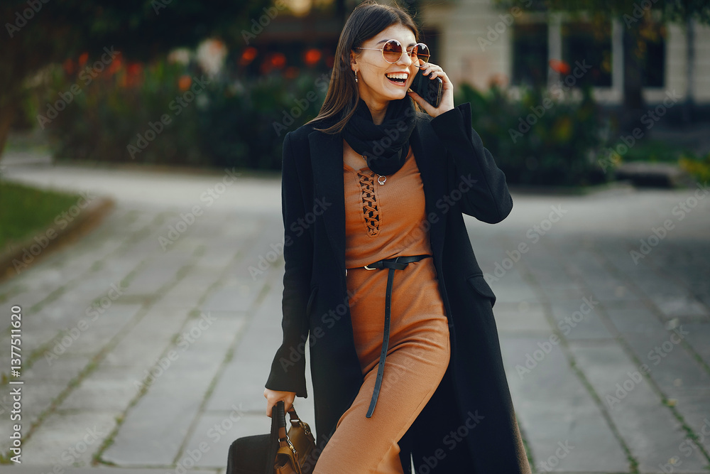 stylish girl walking through the city while using her phone