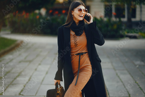 Obraz na płótnie stylish girl walking through the city while using her phone w salonie