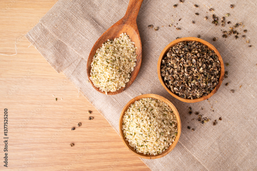 Hemp seeds in wooden spoon and bowls on wooden table, top view. Superfood, healthy tasty organic hemp seeds, source of omega 3 fatty acids, protein. Supplement to healthy diet Hemp seeds in wooden spoon and bowls on wooden table, top view. Superfood, healthy tasty organic hemp seeds, source of omega 3 fatty acids, protein. Supplement to healthy diet