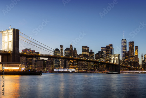 A panoramic sunset view of the Brooklyn Bridge stretching towards Manhattan