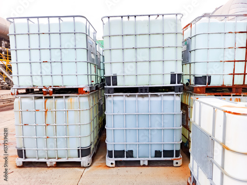 Stacked IBC liquid containers at industrial site. Bulk storage, transport, logistics for chemicals/liquids