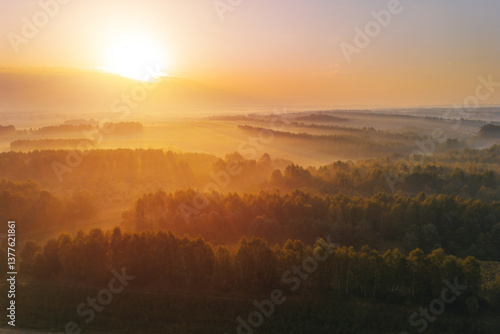 Foggy autumn forest and fields with village in distance