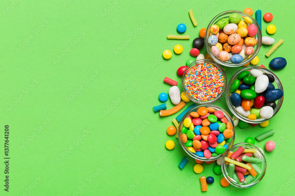 different colored round candy in bowl and jars. Top view of large variety sweets and candies with copy space different colored round candy in bowl and jars. Top view of large variety sweets and candies with copy space