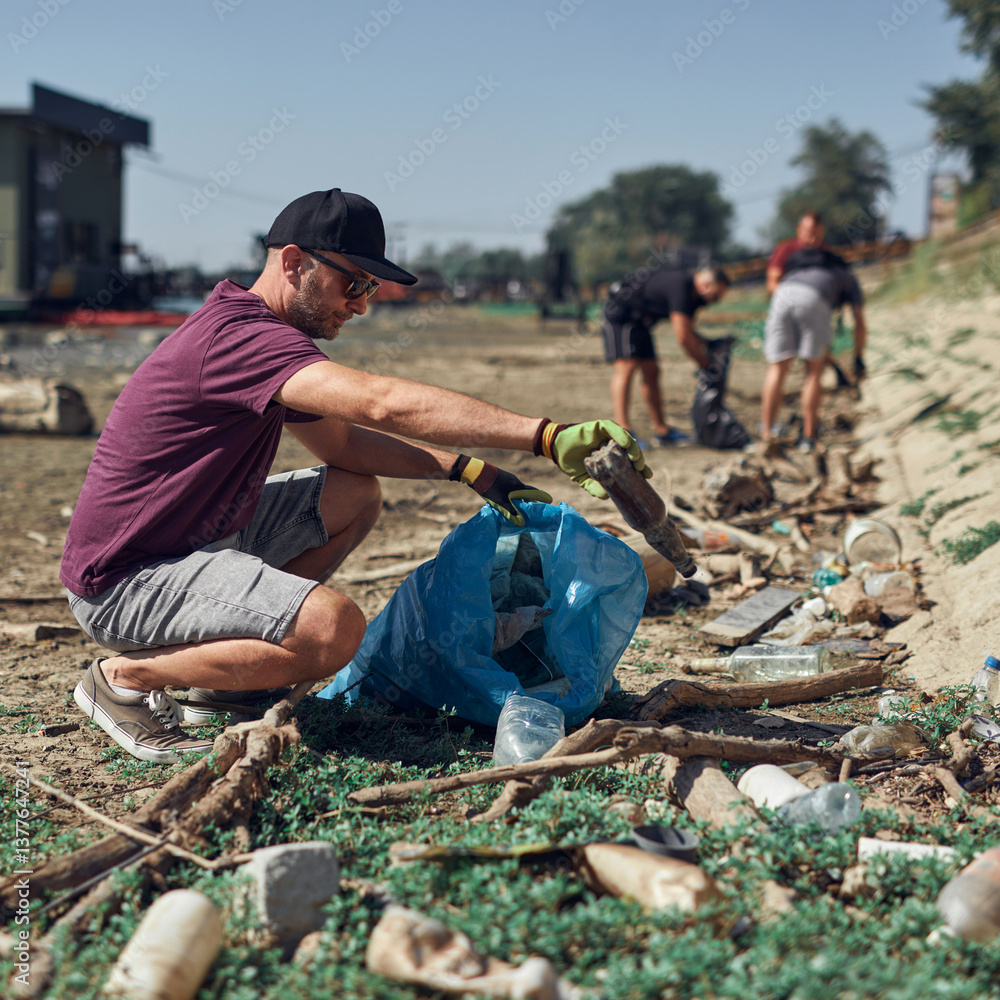Environmental activist cleaning river shore from piled up trash.