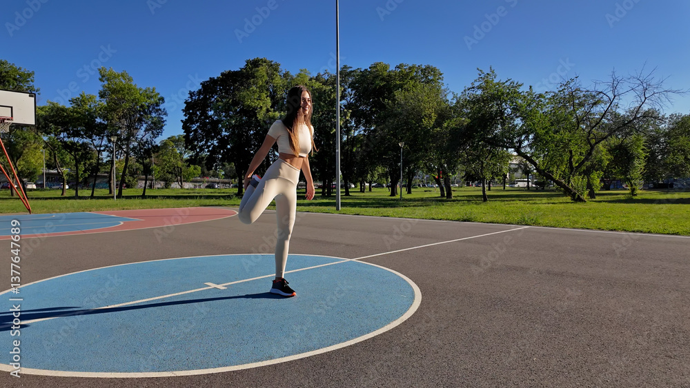 Young woman warming up for exercise and jogging in urban park during sunny summertime day.