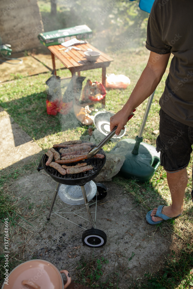 Man preparing barbeque in the garden on a hot summer day.