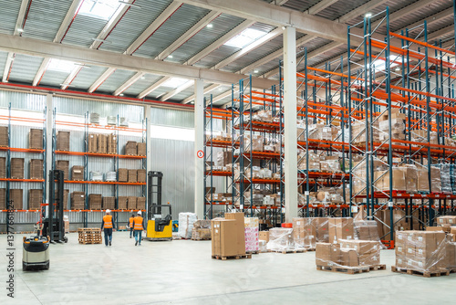 Billede på lærred Warehouse workers managing logistics with forklifts and packages