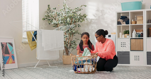 A mother and her daughter sort laundry in the bathroom, folding colorful clothes with care, chatting and smiling while enjoying their quiet time together.
