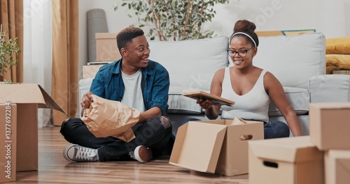 Fotografía In the living room of their new house, a joyful couple sits among cardboard boxes