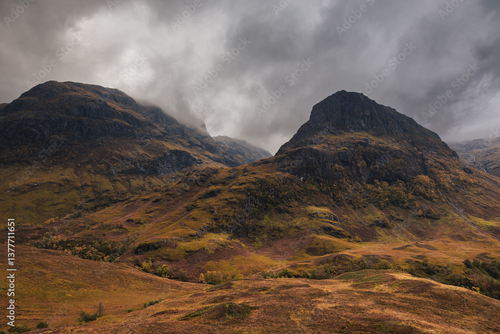 Dramatic peaks and misty valleys define Glen Coe, Scotland’s iconic Highland landscape. Golden light dances on rugged slopes, creating a scene of wild, untamed beauty.