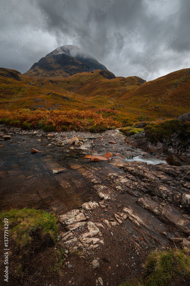Dramatic peaks and misty valleys define Glen Coe, Scotland’s iconic Highland landscape. Golden light dances on rugged slopes, creating a scene of wild, untamed beauty.